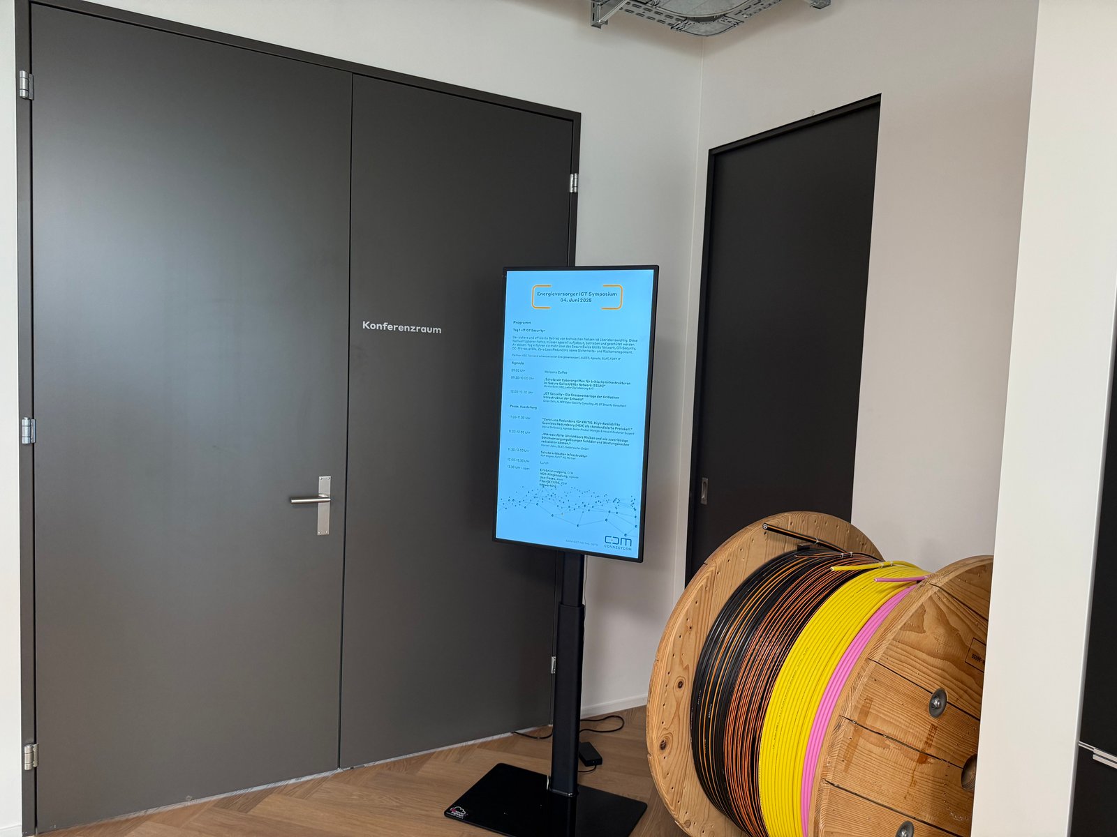 Digitales Tagesprogramm des Energieversorger ICT Symposiums neben dem Konferenzraum